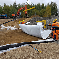 Funcionários que colocam o tapete absorvente de óleo Tektoseal Active com uma travessa de colocação