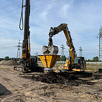 A escavadora enche uma coluna revestida com Ringtrac® com a ajuda de uma tremonha