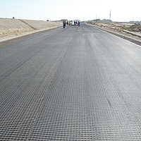 Colocação da grelha HaTelit na superfície da estrada antes de ser asfaltada pelos trabalhadores da construção civil