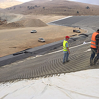 Trabalhadores da construção civil colocam e enchem o tapete de betão Incomat® filter point
