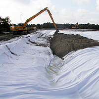 Escavadora espalha o solo sobre o geocomposto Basetrac® Duo