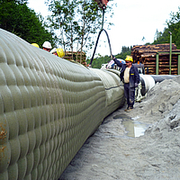 Os trabalhadores enchem a Incomat® Pipeline Cover com a bomba de betão através do gargalo de enchimento