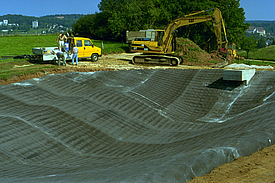 Close-up da instalação de tapetes de concreto para impermeabilização e controle de erosão da bacia de retenção de águas pluviais