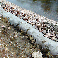 Geotêxtil não tecido e pedras na borda da água para proteção das margens
