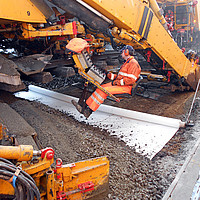 A máquina levanta carris e coloca o geocomposto Basetrac® Duo