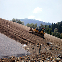 O bulldozer distribui uniformemente o solo sobre uma geogrelha Fortrac para estabilização do solo