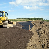 Bulldozer espalha terra sobre uma grelha Basetrac já colocada no estaleiro de construção
