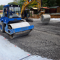 O rolo compacta gravilha e pedra britada sobre o geocomposto Basetrac® Duo-C