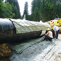 Os trabalhadores fixam a cobertura do oleoduto Incomat® à secção do tubo