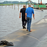 Pessoas caminham sobre uma barragem concluída