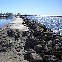 Barragem feita de geossintéticos, revestida com pedras e areia